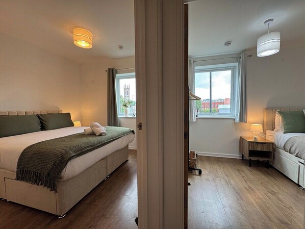 Un dormitorio con cama, mesita de noche y ventana con vista a un edificio.