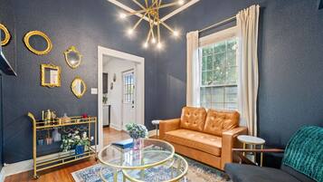A living room with a leather sofa, a glass coffee table, and a gold-framed side table.