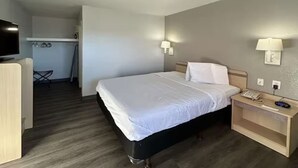 A hotel room with a bed, bedside lamps, a nightstand with a phone, and a television. - Budget-Friendly Stay with Kitchen + Free Parking | Maxey Park - 0.7 mile (Lubbock)