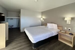 Habitació d'hotel amb llit, làmpades de nit, taulell amb un telèfon i televisió.