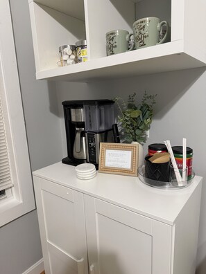 A kitchen counter with a coffee maker, a framed note, and a plant. - Cozy Modern Oasis near Kelley Square (Worcester)