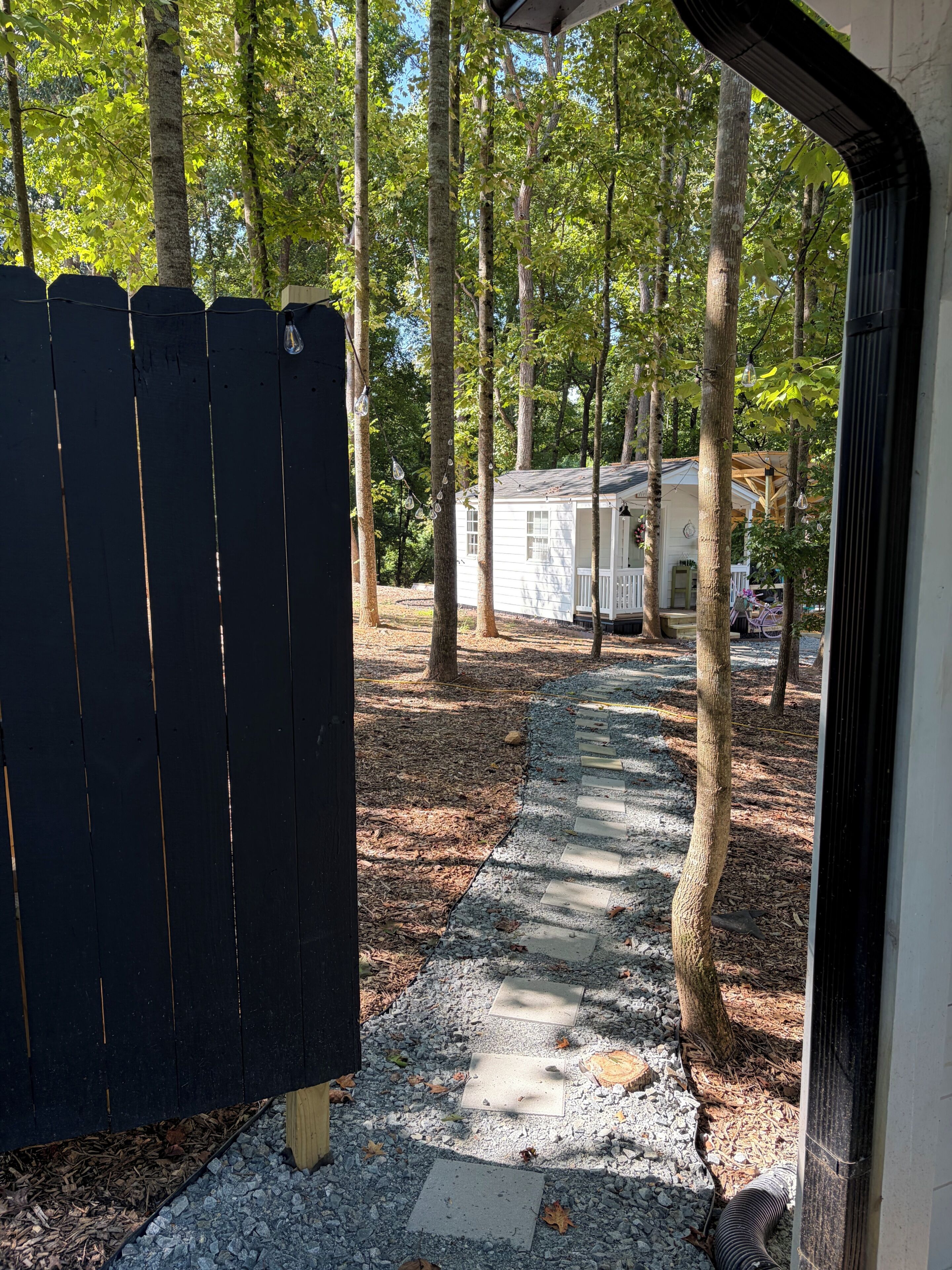 A pathway leading to a white cabin surrounded by trees.