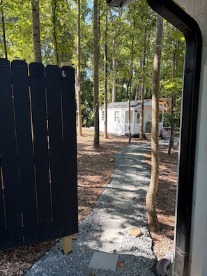 Un sentier qui mène à un chalet blanc entouré d’arbres.