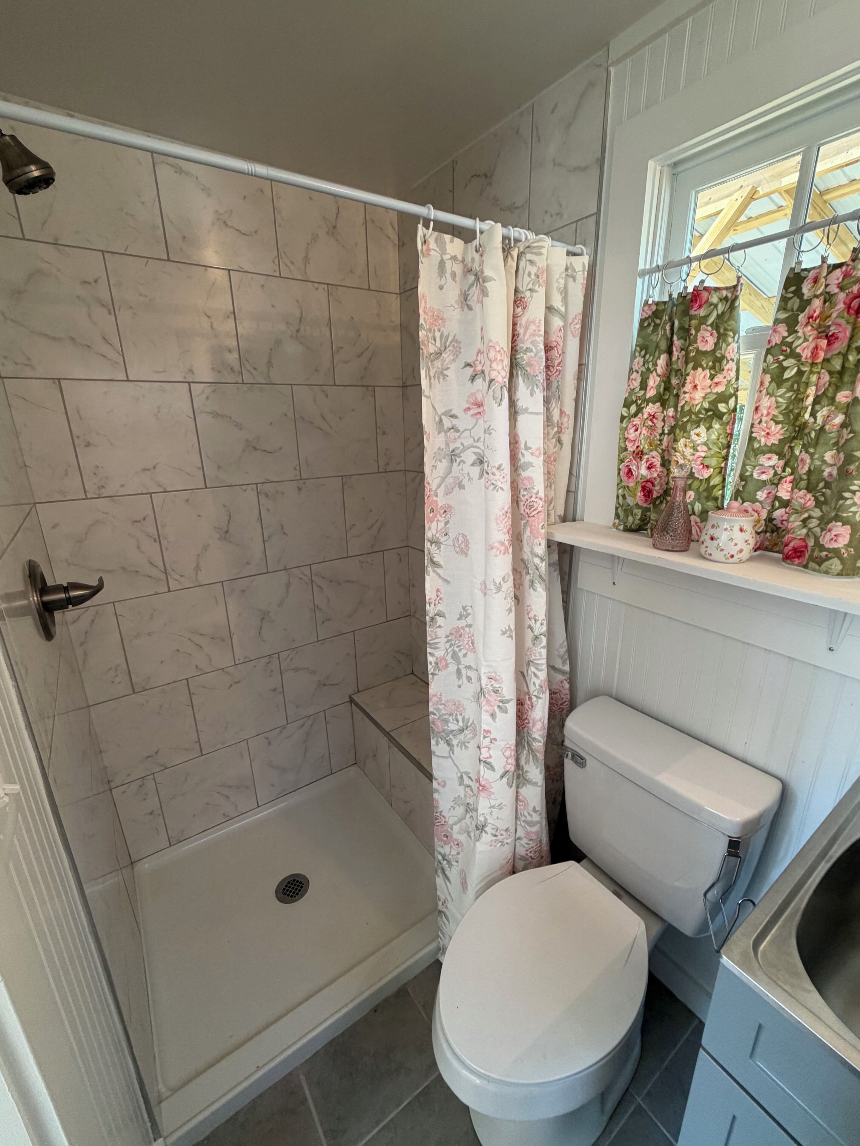 A bathroom with a shower, toilet, and a window with a view.