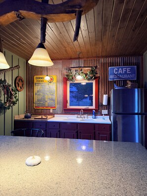 Eine Küche mit einer Granitabdeckung, einer Spüle, einem Kühlschrank und einem Schild, das ein Café-Restaurant anzeigt.
