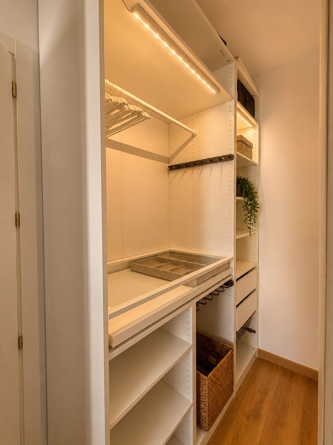 Un vestidor amplio con repisas abiertas, una barra para colgar ropa y un zapatero.