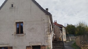 Un edificio con fachada de piedra, puerta de madera y una ventana pequeña.
