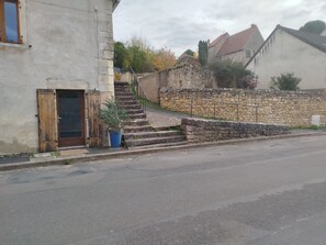 A residential street with a stone wall, a wooden door, and a potted plant.