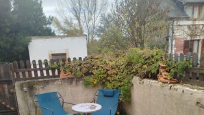 Un patio con una mesa redonda, dos sillas y un adorno pequeño.