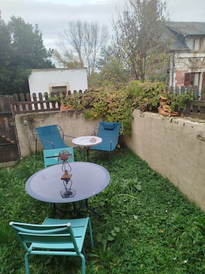 Een terras met een ronde tafel, twee stoelen en een klein decoratief object.