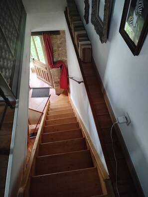 A wooden staircase leading to a room with a window, a red curtain, and a wall-mounted power outlet.