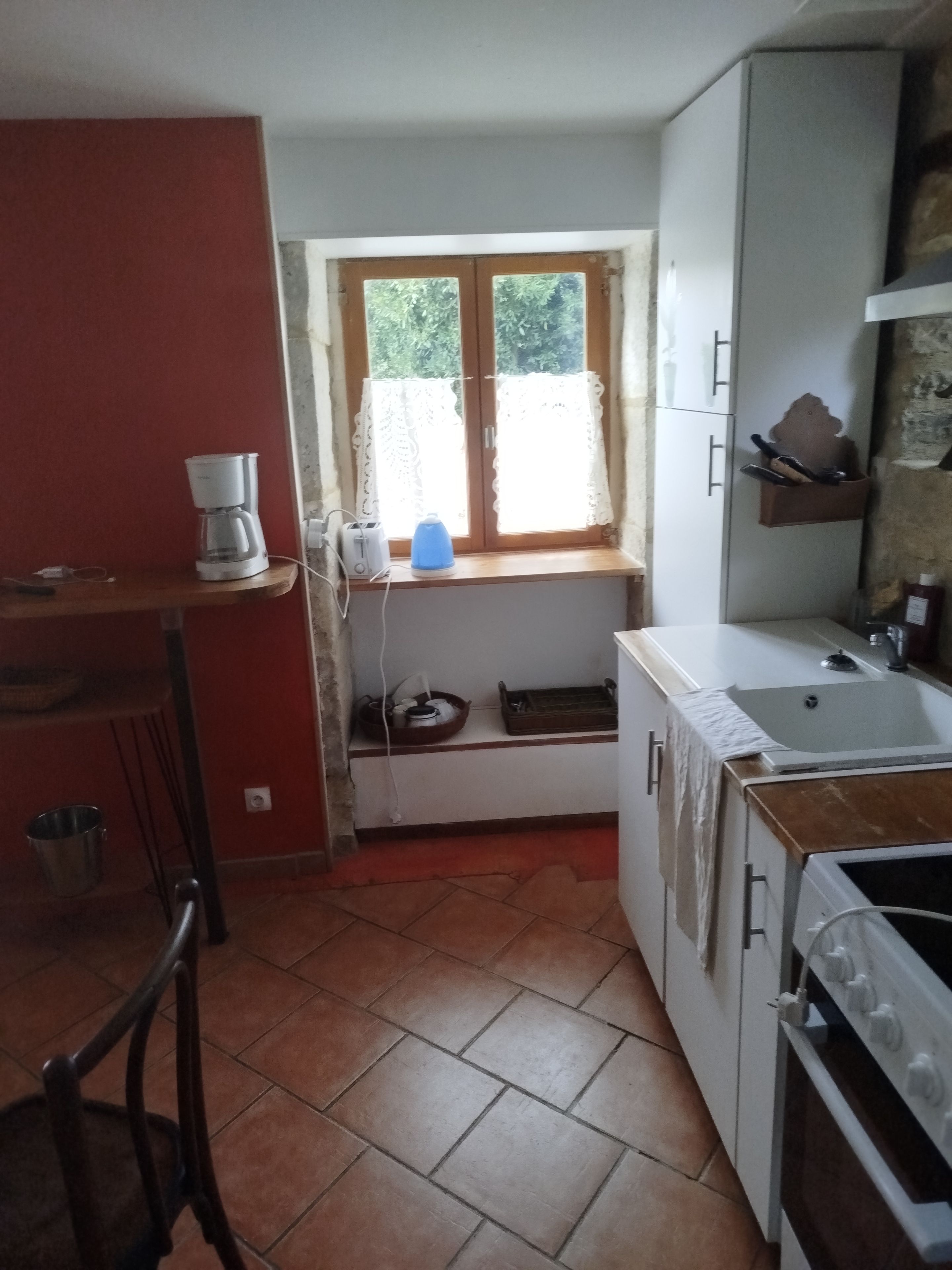 A compact kitchen with a window, a coffee maker, a sink, and a stove.