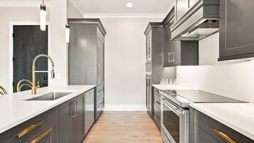 A modern kitchen with stainless steel appliances, a white countertop, and a wooden floor.