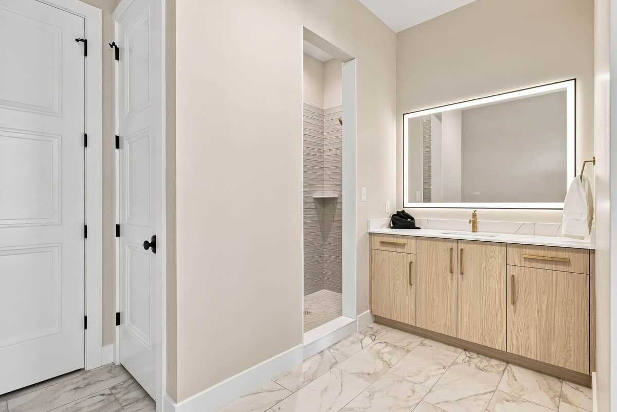 Une salle de bain dotée d’un grand miroir, de meubles en bois et d’un espace douche.