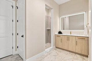 A bathroom with a large mirror, wooden cabinets, and a shower area.