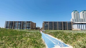 Un ensemble immobilier moderne composé de plusieurs étages, avec un chemin bleu menant à l’entrée.