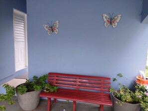 Eine rote Bank vor einer blauen Wand mit zwei Schmetterlingsdekorationen.