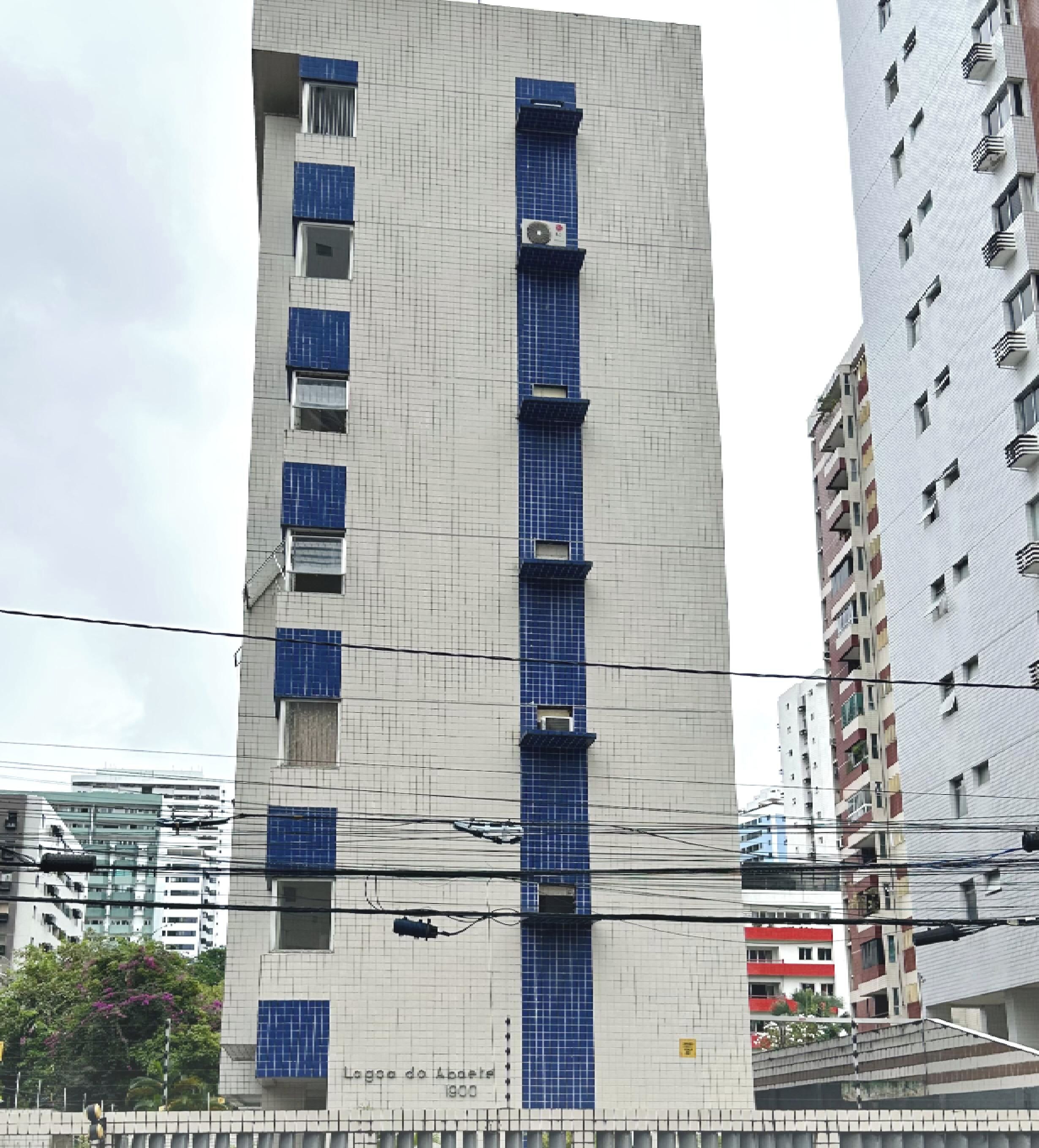 Un edificio alto con fachada de diseño enrejado, múltiples balcones y un cartel que indica 'Lagoa do Abade 1900'.