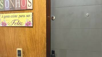 A wooden door with a sign that reads 'Família Amor Sonhos' and a metal door with the number '402' and a logo for 'HOSPEDAGENS E ADMINISTRAÇÃO'.