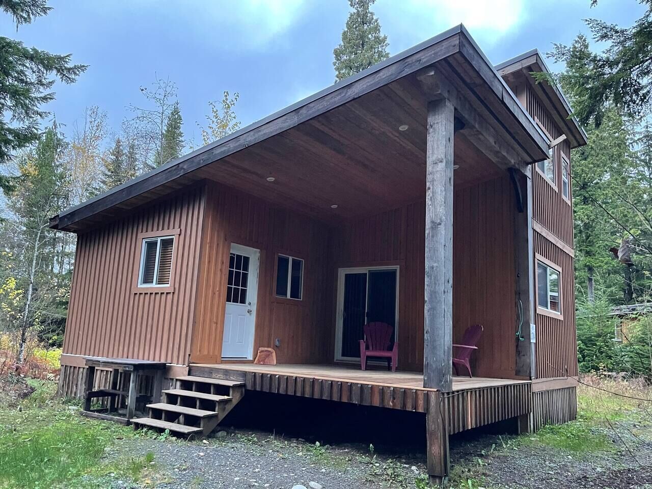 A wooden cabin with a porch, a door, and a window.