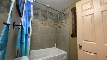 A bathroom with a bathtub, shower, and toilet.