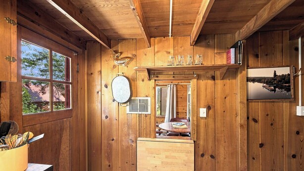 A wooden interior with a window, a mirror, and a shelf with books and glasses. - Cozy Lakeside Cabin: Dock, Deck, & Pet Friendly (McCall)