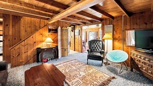 A wooden interior with a TV, a chair, and a patterned rug. - Cozy Lakeside Cabin: Dock, Deck, & Pet Friendly (McCall)