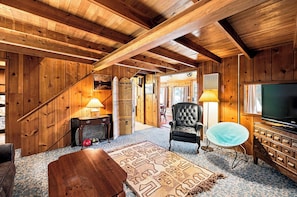 A wooden interior with a TV, a chair, and a patterned rug. - Cozy Lakeside Cabin: Dock, Deck, & Pet Friendly (McCall)