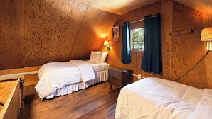A cozy attic bedroom with wooden walls, two beds, a nightstand, a lamp, and a window with curtains. - Cozy Lakeside Cabin: Dock, Deck, & Pet Friendly (McCall)