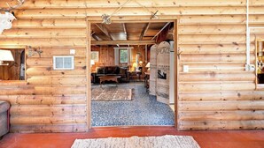 A log cabin interior with a living room, a fireplace, and a dining area. - Cozy Lakeside Cabin: Dock, Deck, & Pet Friendly (McCall)