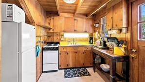 A compact kitchen with wooden cabinets, a refrigerator, a stove, and a sink. - Cozy Lakeside Cabin: Dock, Deck, & Pet Friendly (McCall)