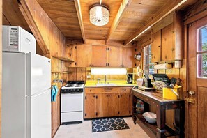 A compact kitchen with wooden cabinets, a refrigerator, a stove, and a sink. - Cozy Lakeside Cabin: Dock, Deck, & Pet Friendly (McCall)