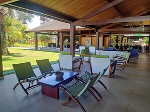 An outdoor seating area with tables and chairs, a covered patio, and a view of a landscaped garden. - Malawi Muro Alto, ground floor apartment (N. Sra. do Ó)