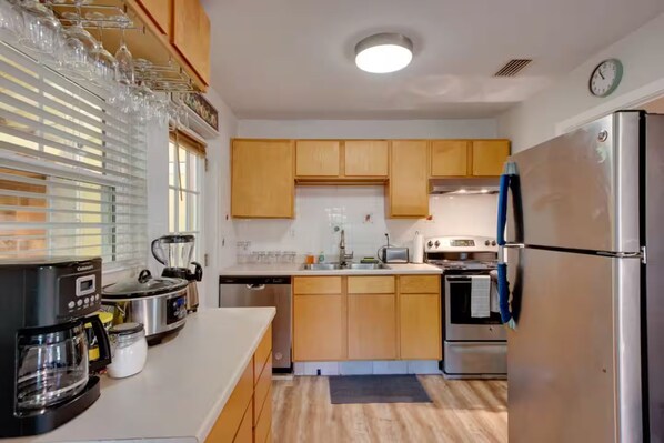 A kitchen with wooden cabinets, a stainless steel refrigerator, a coffee maker, and a blender.