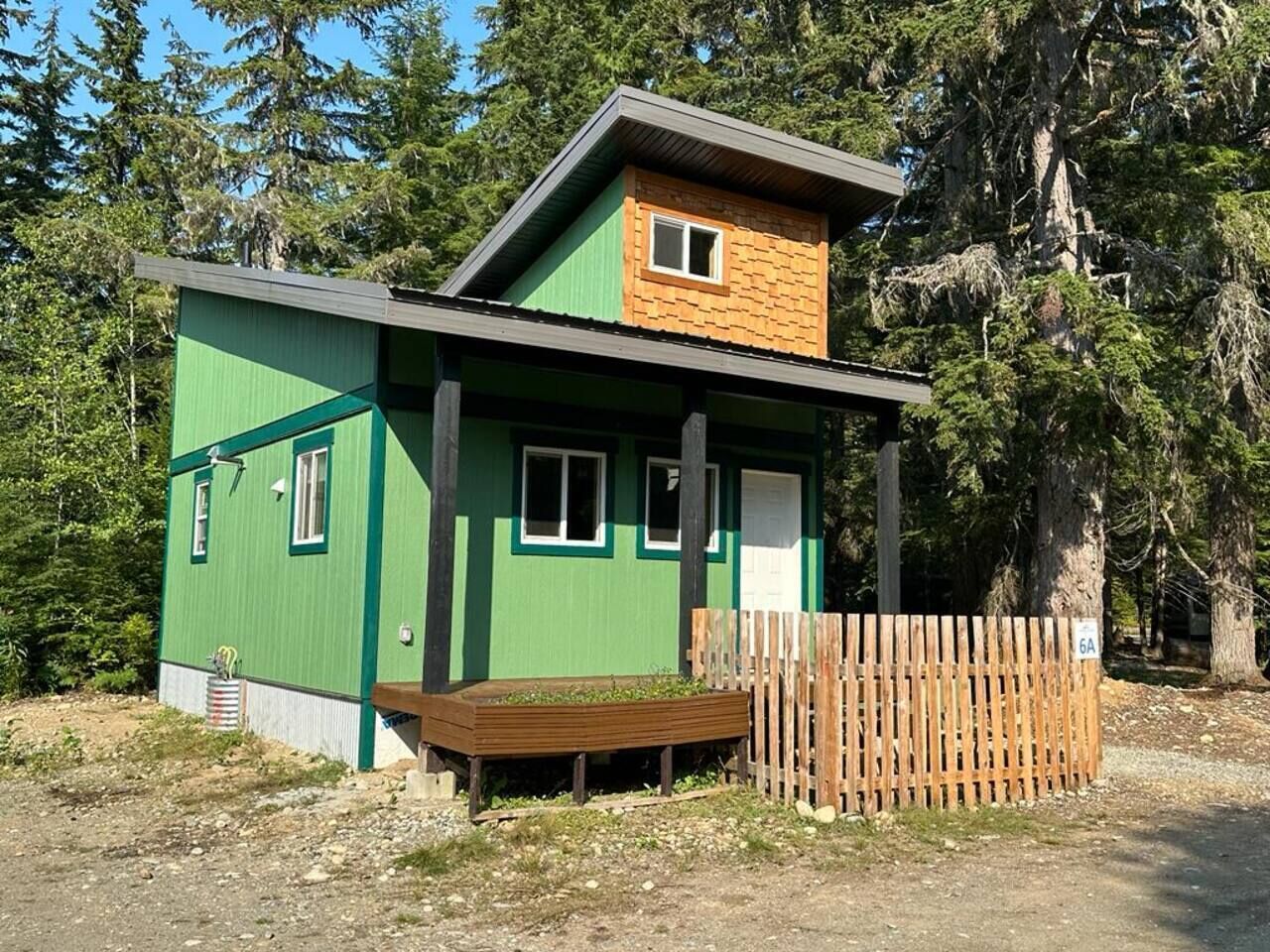 A small, single-story building with a green exterior and a wooden deck.