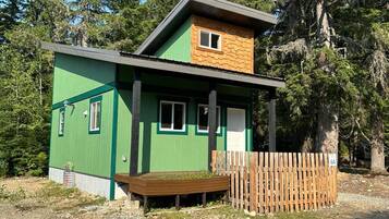 A small, single-story building with a green exterior and a wooden deck.