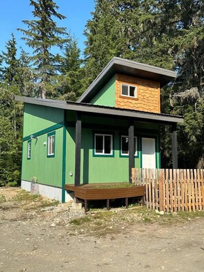 A two-story house with a green exterior and a wooden deck.