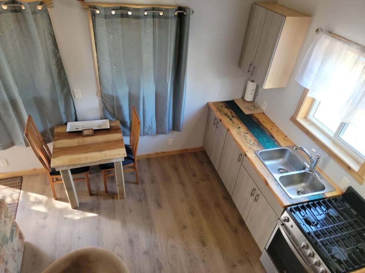 A compact kitchen with a dining table, chairs, a sink, and a stove.