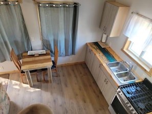 A compact kitchen with a dining table, chairs, a sink, and a stove.
