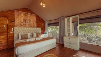Un dormitorio con una cama grande, cabecera de madera con estampado de leopardo, un armario y una ventana con vistas a árboles.