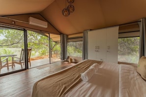 A bedroom with a large bed, a sliding glass door leading to an outdoor area, and a ceiling fan. - Wilpattu Wilderness Camping - Tent 2 (Wilpattu)