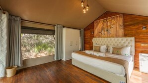 Een slaapkamer met een groot bed, houten wanden, een plafondlamp en een raam met gordijnen.