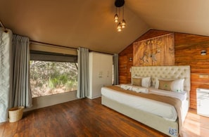 A bedroom with a large bed, wooden walls, a ceiling light, and a window with curtains. - Wilpattu Wilderness Camping - Tent 2 (Wilpattu)