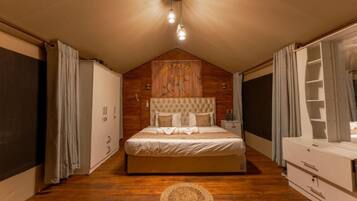 A bedroom with a wooden ceiling, a bed with a headboard, a bedside table, a wardrobe, and a window with curtains.