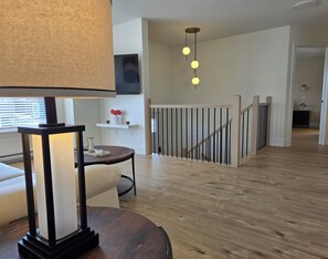 Ein modernes Wohnzimmer mit einem runden Tisch, einer Couch, einer Lampe und einer Treppe mit Geländer.
