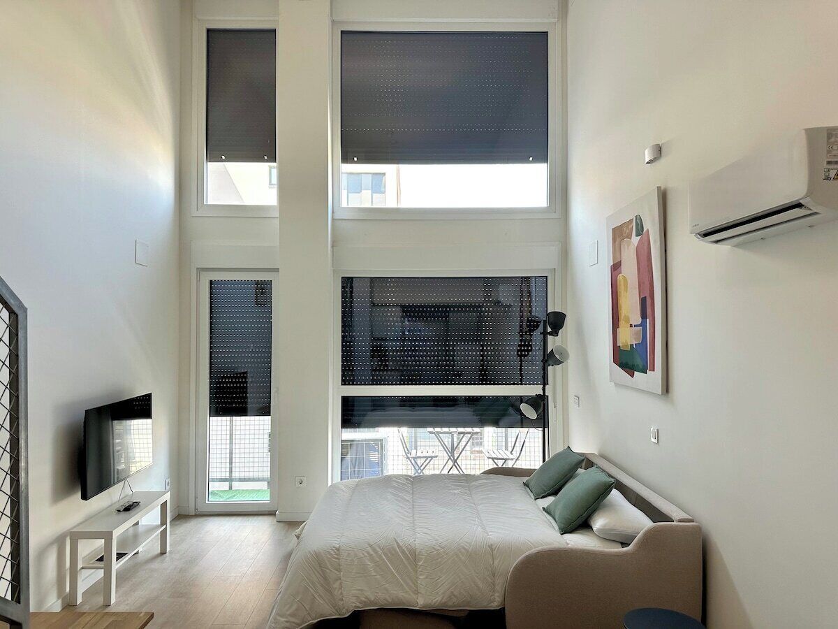 Une chambre avec un lit, une télévision, un canapé et un balcon offrant une vue.