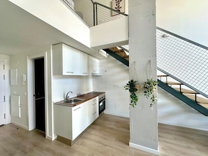 Une cuisine moderne avec des meubles blancs, un plan de travail en bois et un four encastré.
