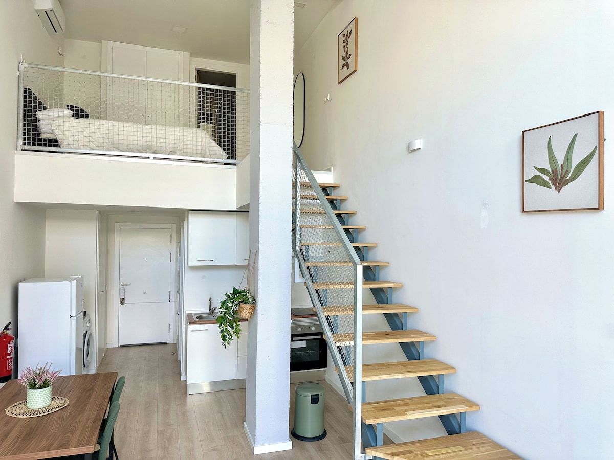 Un espacio habitable compacto con literas, kitchenette, comedor y una escalera.