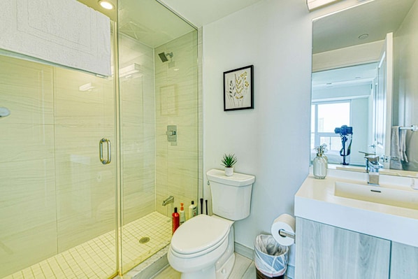 Une salle de bain moderne avec une douche à parois de verre, des toilettes et un lavabo avec un miroir.