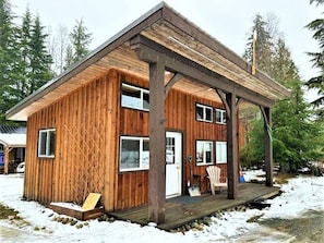 A wooden cabin with a covered porch, a door, and windows.